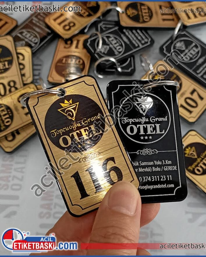 Topcuoğlu Grand Otel için üretilen, otel anahtarlığı ürünümüz, altın renk metal ile bir yüzey baskıları yapılmış, dayanaklığı arttırmak için 5mm pleksi malzemeden taban oluşturulmuştur, otel anahtarlık baskıları lazer ile çıkmaz, silinmez, kazınmaz olarak üretildi, uzun yıllar kullanılabilen, şimdiye kadar hiç şikayet üretmeyen kaliteli bir üründür, otel anahtarlık, metal etiket, 5 mm pleksi ile özel tasarım otel anahtarlığı yapılmıştır, pleksi üzerine lazer ile çıkmaz, silinmez, kazınmaz baskılar yapılmıştır