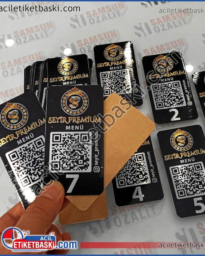 siyah QR kod baskılı masa için, menü etiket baskısı, metal etiket, siyah renk ürün, üzerinde altın ve gümüş renk baskıları var, acil etiket baskı merkezi, Seyir Premium Kafe için yapılan, QR ile menüye ulaşılabilen, metal masa üzeri etiket baskısı, özel ebat ve renk çalışılmıştır, adet ve ebada göre fiyat alınız black QR code printed for table, menu label printing, metal label, black color product, gold and silver color prints on it, urgent label printing center, made for Seyir Premium Cafe, menu can be accessed with QR, metal table label printing, special size and color are worked on, get price according to quantity and size