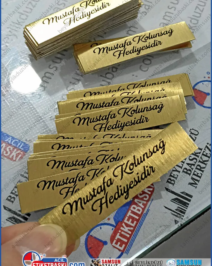 altın metal etiket, fırçalı sarı etiket, tablo künyesi baskı, paslanmaz marka etiketi, lüks ürün etiketi, dekoratif metal plaka, kaliteli logo baskı, mobilya marka etiketi
